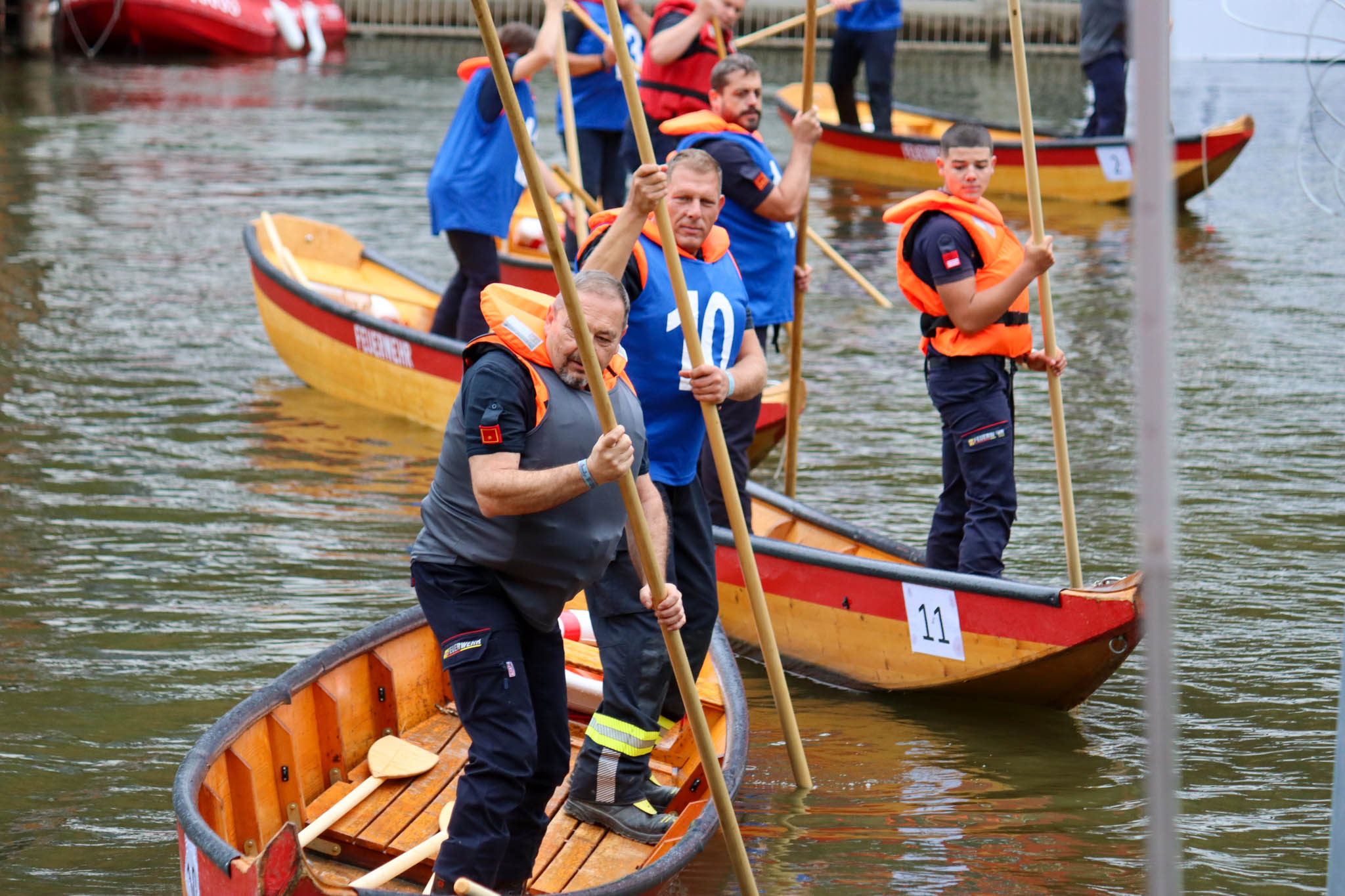 Feuerwehrleute mit Stechpaddeln in Booten auf einem Fluss bei einem Bewerb.